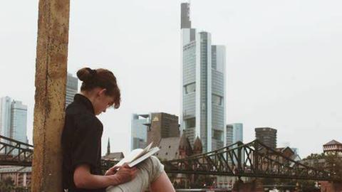 Lesende junge Frau am Ufer des Main in Frankfurt