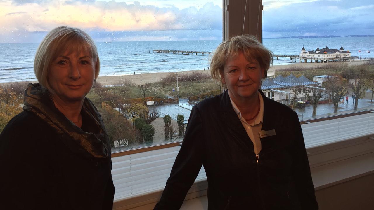 Beate-Carola Johannsen, Vorsitzende des Tourismusverbands Usedom, und Hoteldirektorin Petra Bensemann stehen vor einem Fenster mit Blick aufs Meer.