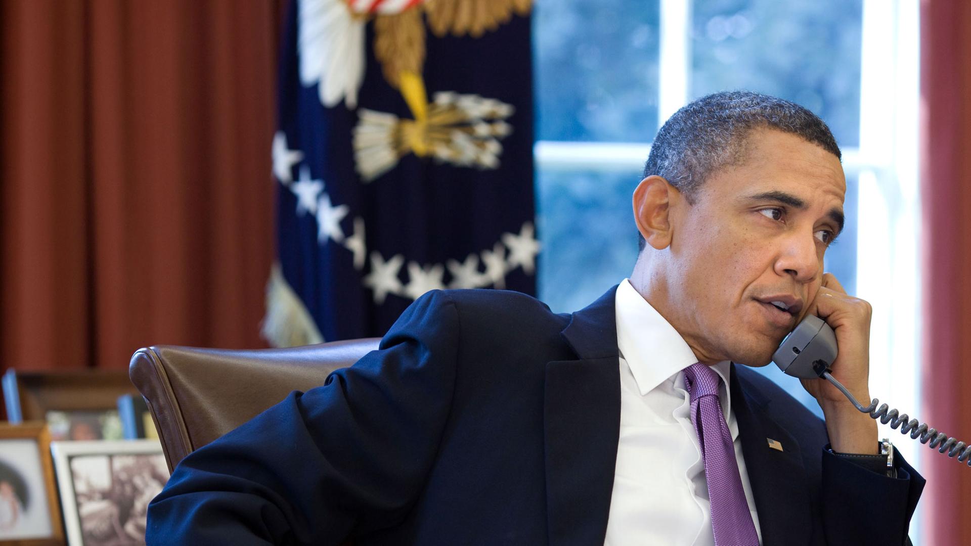 US-Präsident Barack Obama sitzt an seinem Schreibtisch im Oval Office, in der linken Hand hält er den Telefonhörer.