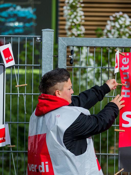 Eine Erzieherin der Kindertagesstätte "Kirschblüte" hängt in Schwerin ein Streik-Plakat an den Eingang der Einrichtung.
