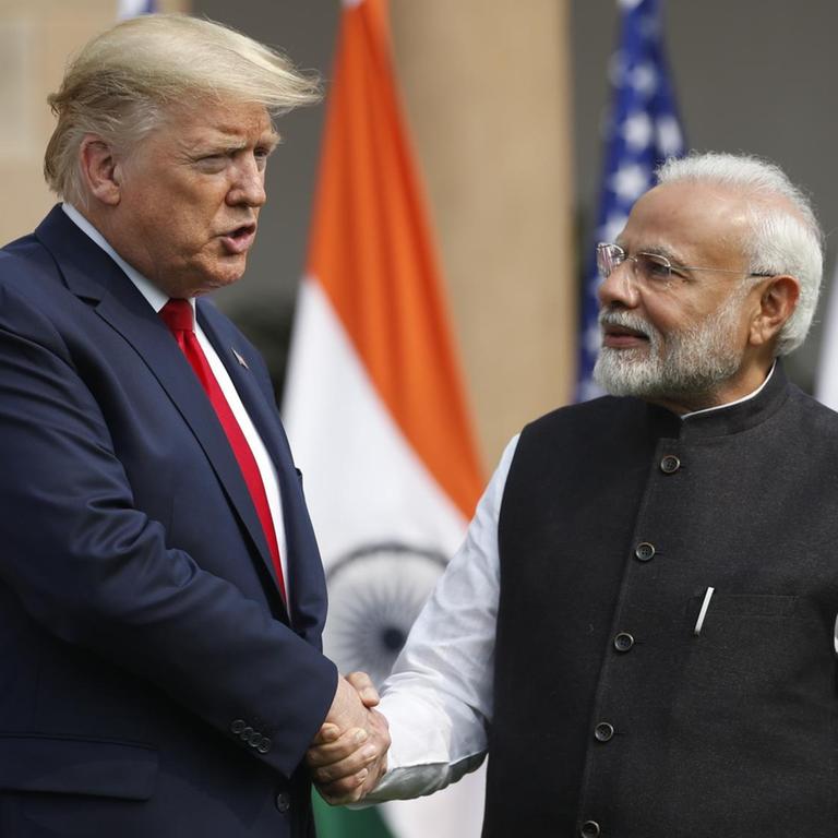 US-Präsident Trump schüttelt dem indischen Premierminister Modi die Hand. Ihnen ihnen die Flaggen der beiden Länder.