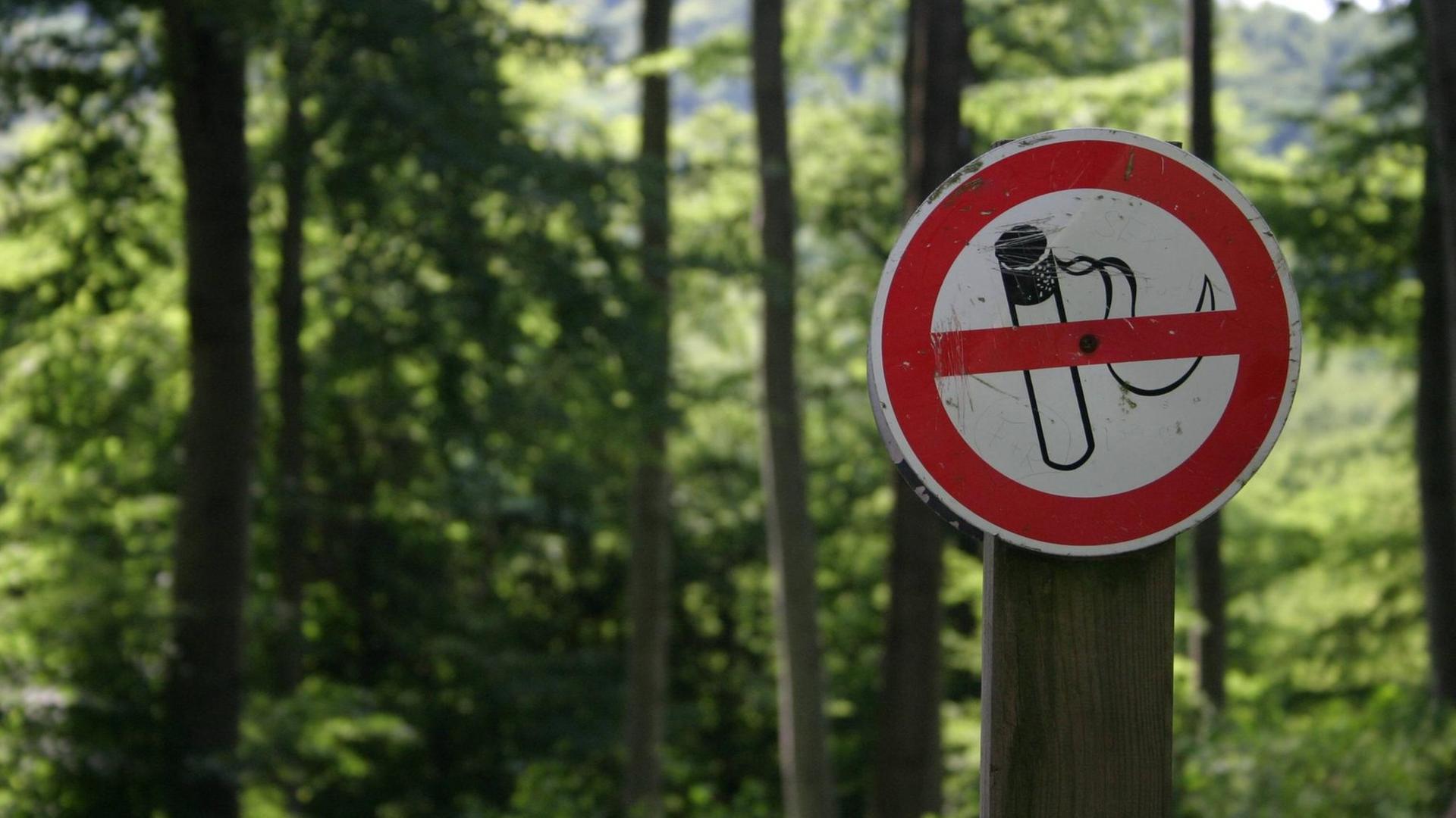 Ein Schild "Rauchen verboten" hängt im Wald.