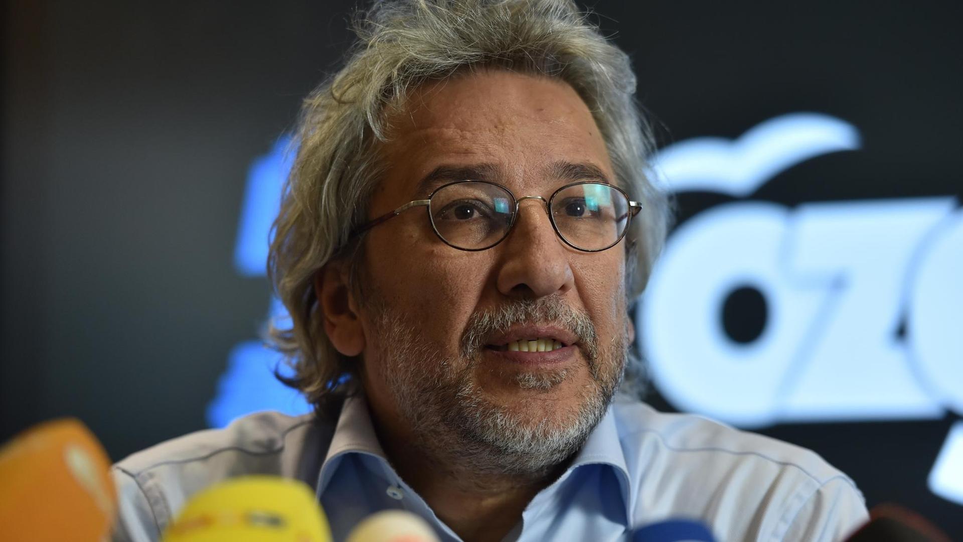 Der Journalist Can Dündar hinter einem Wald von Mikrofonen.