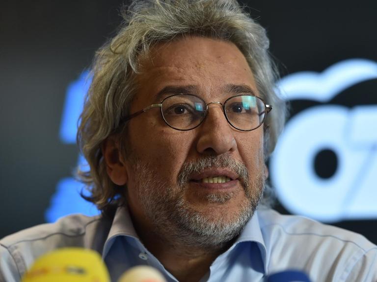 Der Journalist Can Dündar hinter einem Wald von Mikrofonen.
