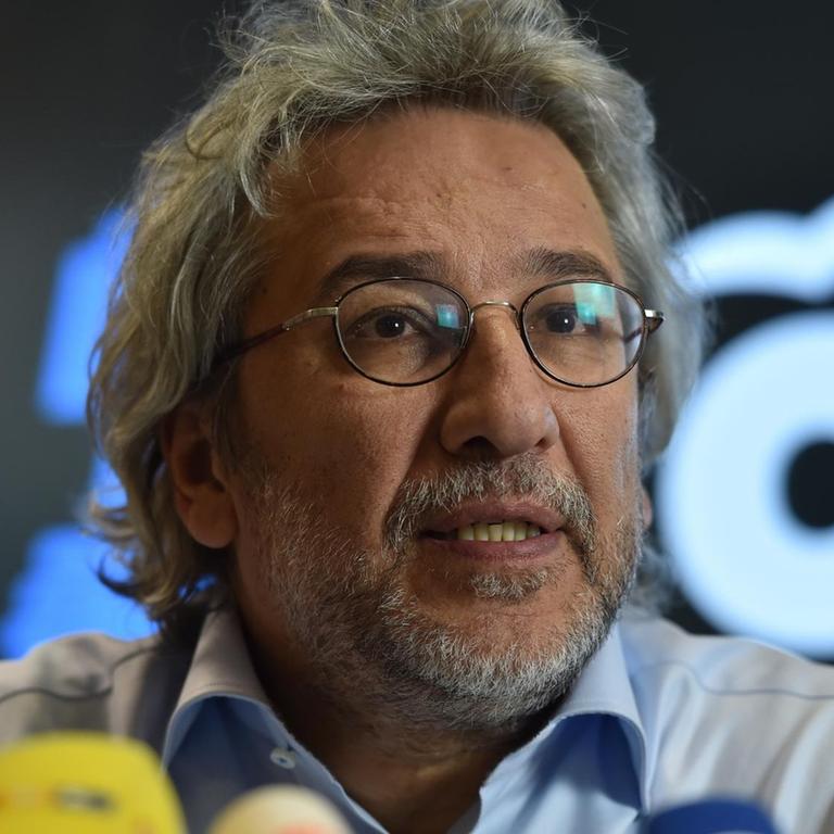Der Journalist Can Dündar hinter einem Wald von Mikrofonen.