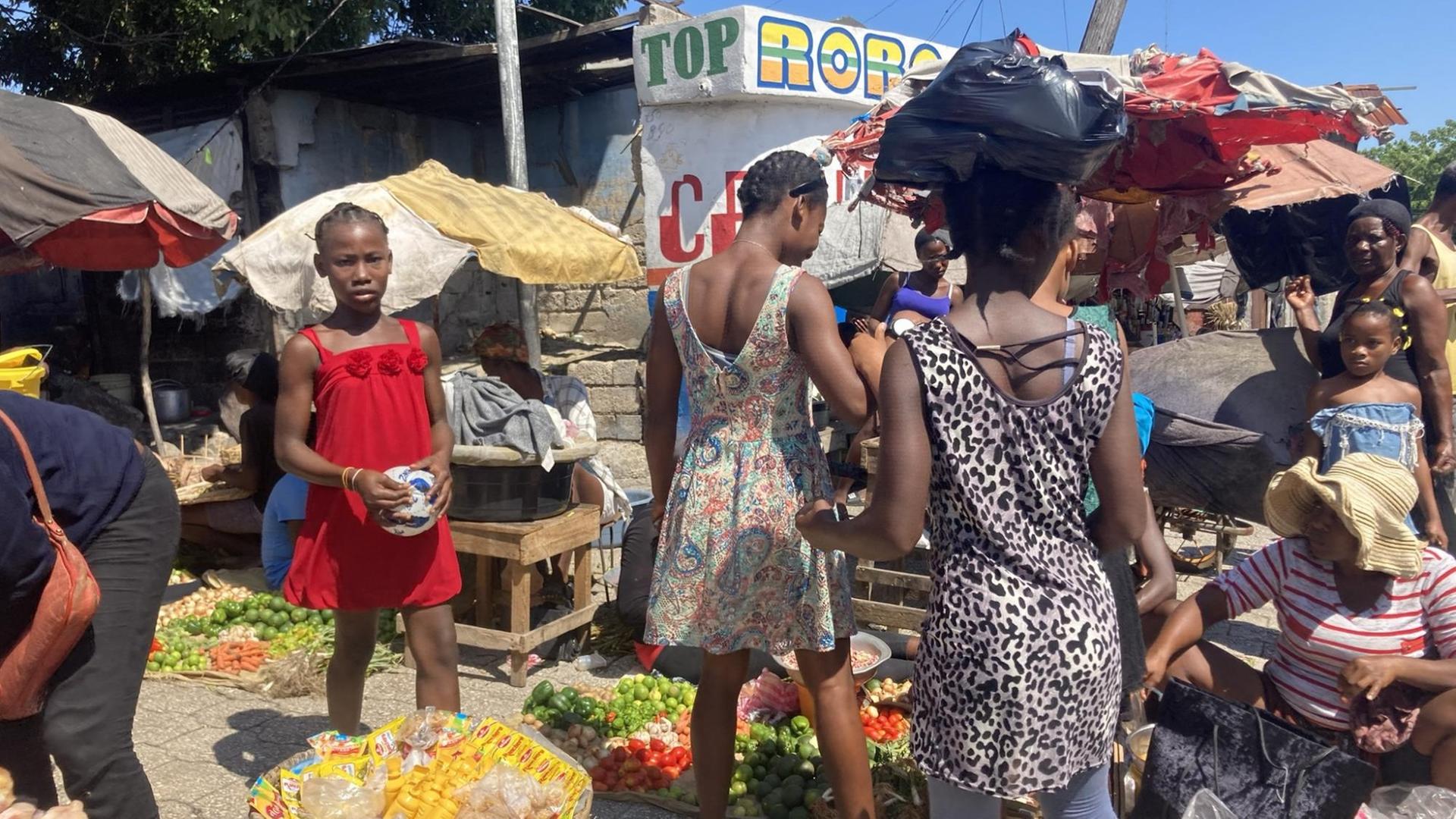 Frauen in bunten Kleidern begutachten die Ware auf einem Markt. Frauen in bunten Kleidern begutachten die Ware auf einem Markt.