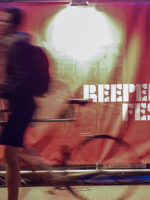 Ein Passant schiebt am 20.09.2017 in Hamburg vor dem Theater "Schmidtchen" sein Fahrrad vor dem Logo des Reeperbahn Festivals entlang. Das Festival findet vom 20. bis 23. September 2017 in der Hansestadt statt.