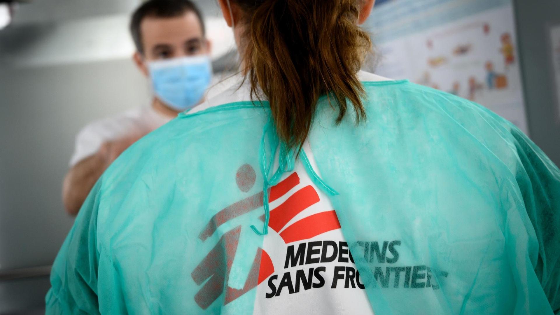 Ärzte stehen einander gegenüber, auf dem Rücken eines Kittels prangt die Aufschrift "Medecins sans Frantières". Ärzte stehen einander gegenüber, auf dem Rücken eines Kittels prangt die Aufschrift "Medecins sans Frantières".