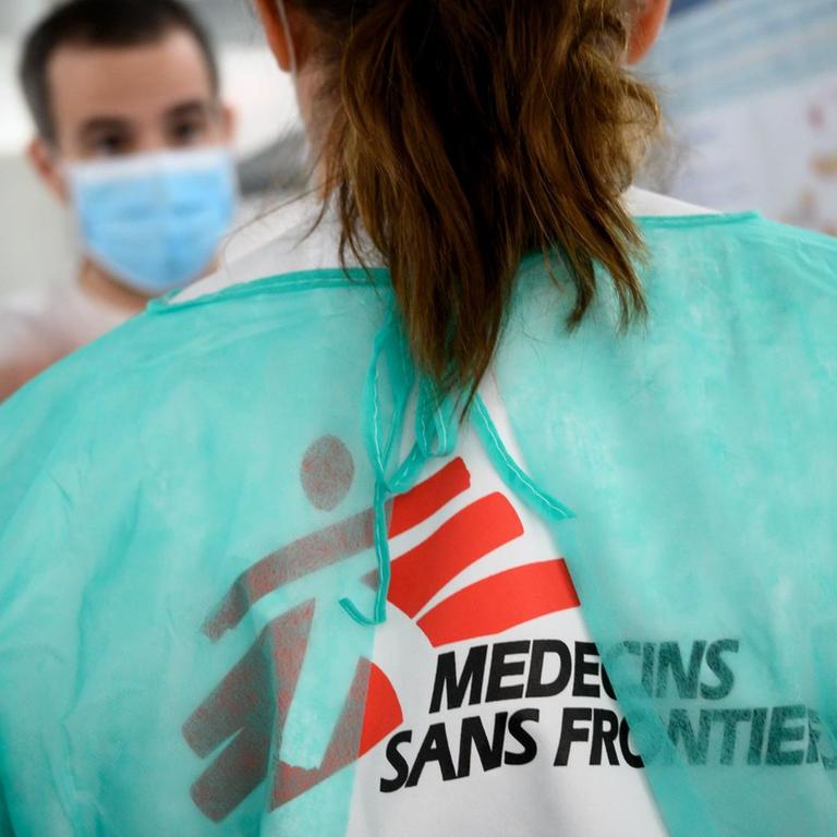 Ärzte stehen einander gegenüber, auf dem Rücken eines Kittels prangt die Aufschrift "Medecins sans Frantières".
