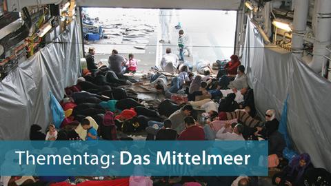 Schiffbrüchige, die am 06.06.2015 von Soldaten der Fregatte "Hessen" aus dem Mittelmeer gerettet wurden, sitzen an Bord des Schiffes im Schaten. Deutsche, italienische und internationale Einsatzkräfte haben im Mittelmeer bei mehreren Rettungsaktionen Tausende Flüchtlinge in Sicherheit gebracht.