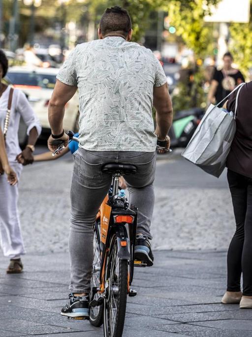 Ein Fahrradfahrer fährt auf einem Gehweg zwischen Passanten in Berlin-Kreuzberg.