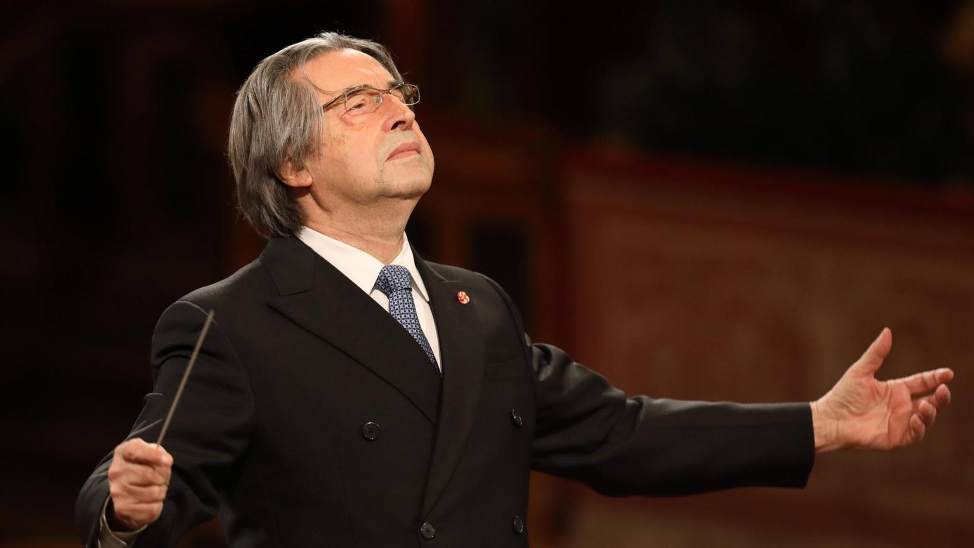 Dirigent Riccardo Muti steht mit geöffneten Armen und leicht in den Nacken gelegtem Kopf am Dirigentenpult der Wiener Philharmoniker im Jahr 2021.