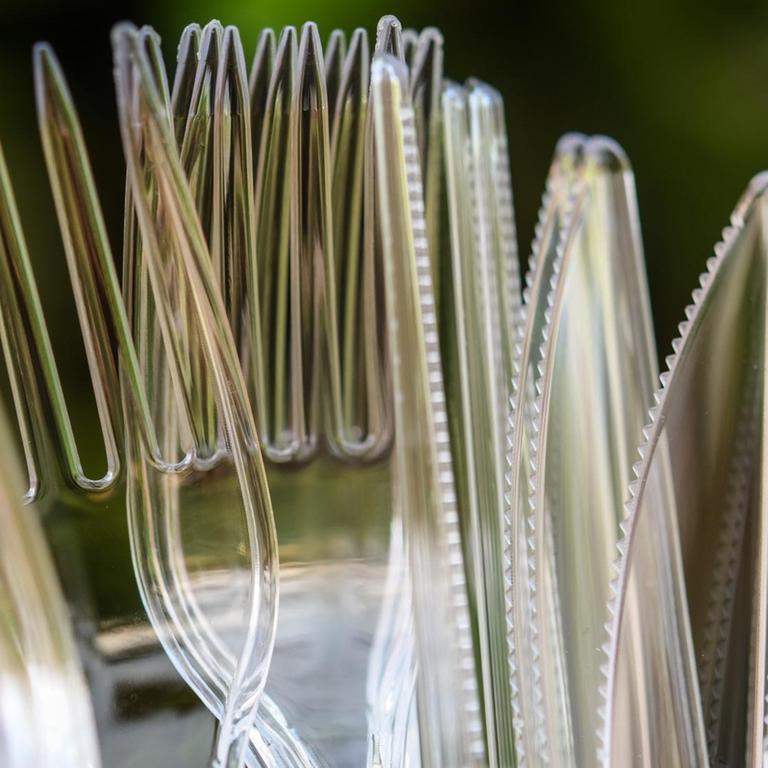 Messer und Gabeln aus Plastik stehen in einem Kunststoffbecher