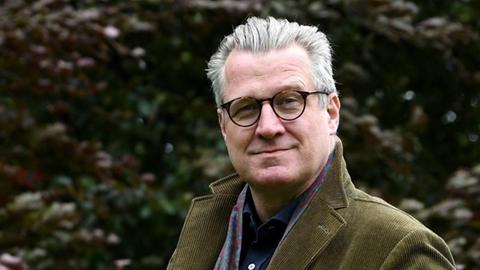 Der Historiker und Schriftsteller Philipp Blom steht vor einer Hecke und schaut in die Kamera.