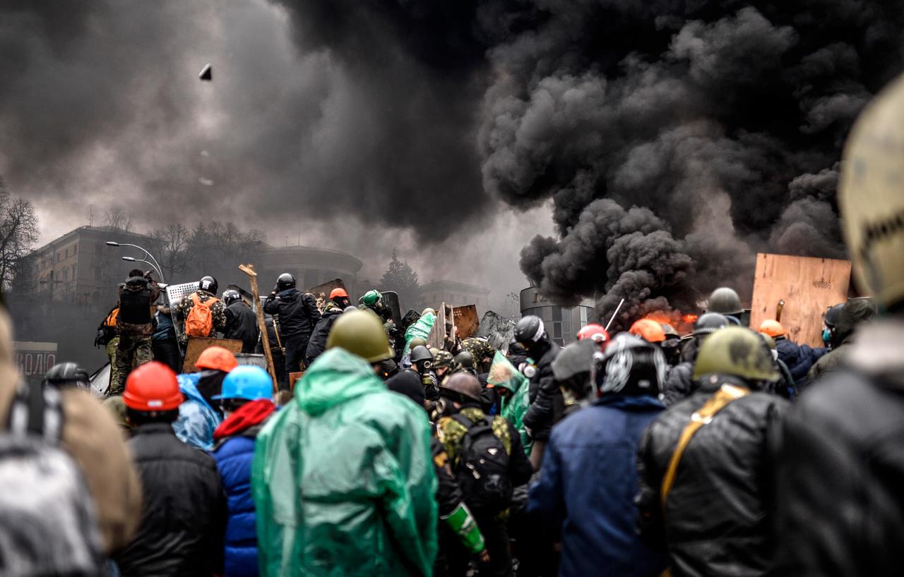 Demonstranten versammeln sich hinter brennenden Barrikaden in Kiew