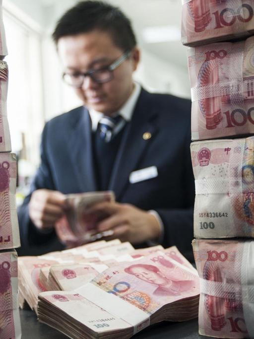 Ein chinesischer Bankmitarbeiter zählt Renminbi-Yuan-Geldscheine