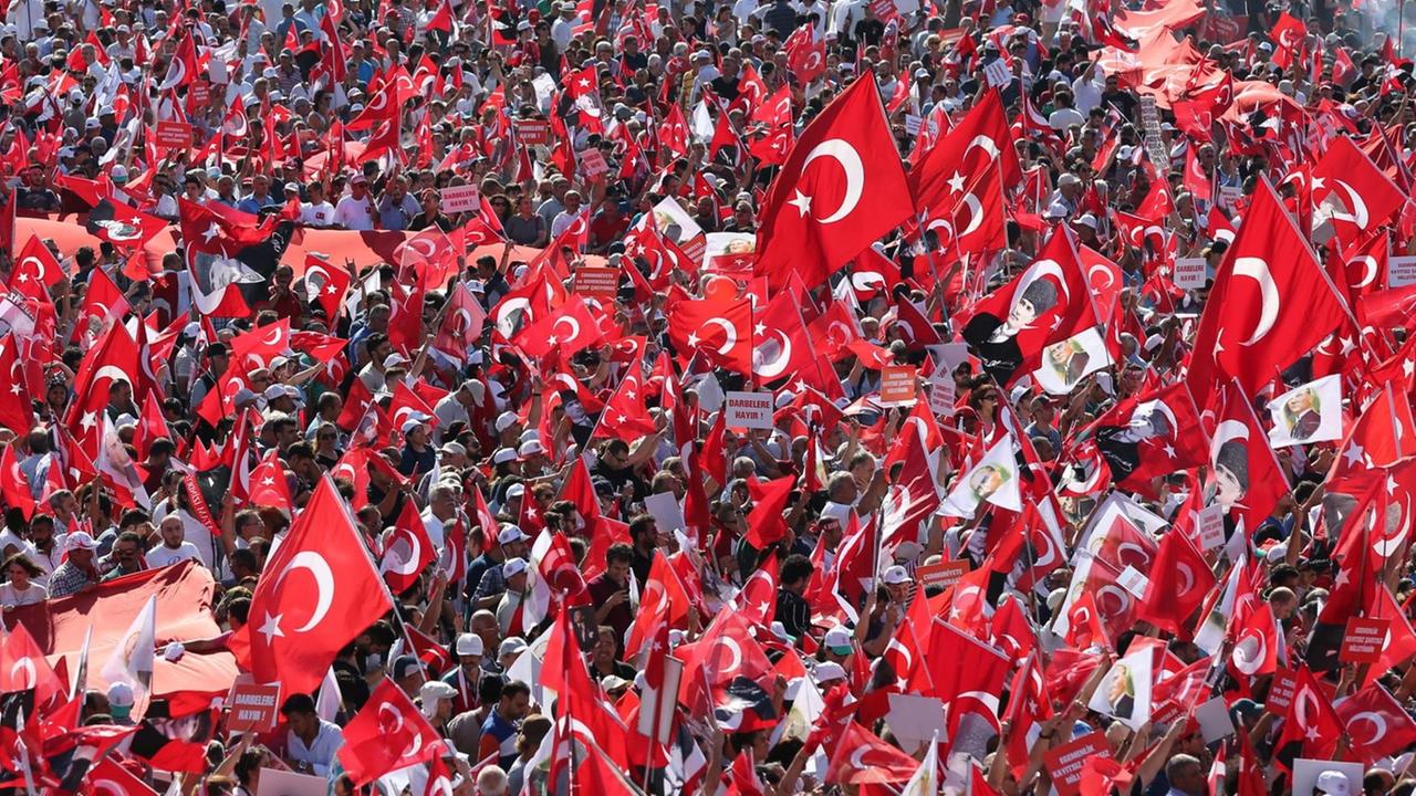Zehntausende Menschen demonstrieren in Istanbul, viele halten die Nationalfahne und Bilder von Staatsgründer Atatürk in die Luft.