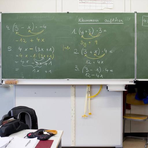 Vollgeschriebene Schultafel mit mathematischen Gleichungen.