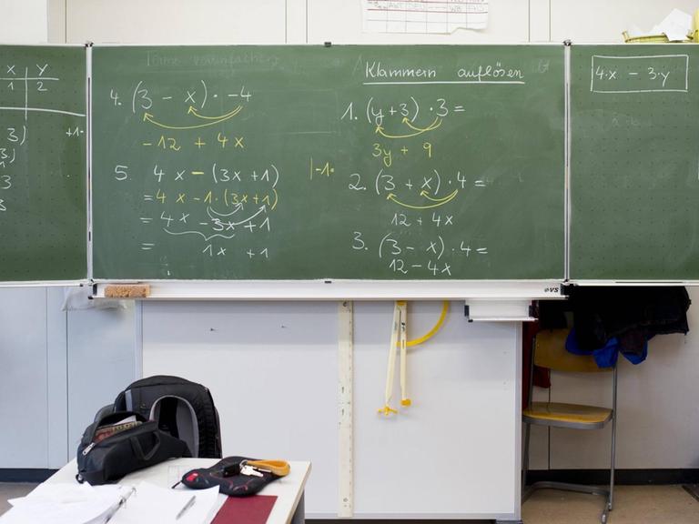 Vollgeschriebene Schultafel mit mathematischen Gleichungen.