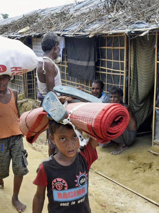 Geflüchtete Rohingya tragen in einem Camp in Cox's Bazaar im Südosten von Bangladesch verteilte Hilfsgüter.