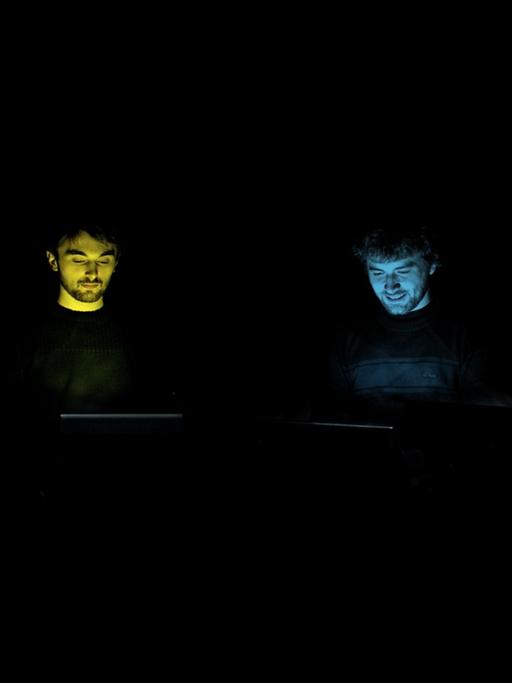 Die Gesichter der Mitglieder der Band "Benoît and the Mandelbrots" bunt ausgeleuchtet vor schwarzem Hintergrund
