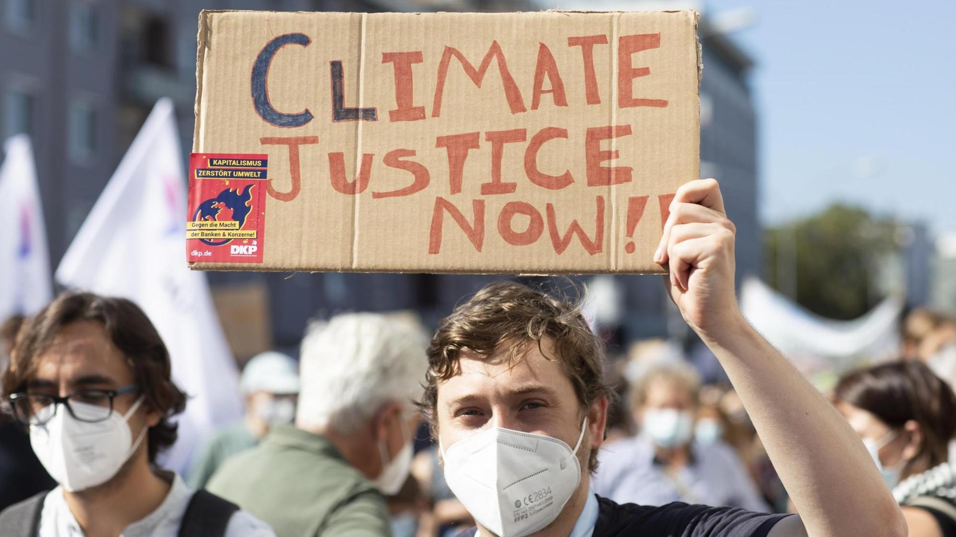 Fridays for future Demonstration gegen Klimawandel. Ein Jugendlicher hält ein Pappschild mit der Aufschrift "Climate Justice" hoch.