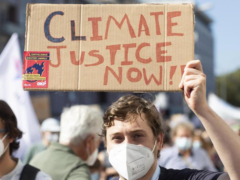 Fridays for future Demonstration gegen Klimawandel. Ein Jugendlicher hält ein Pappschild mit der Aufschrift "Climate Justice" hoch.