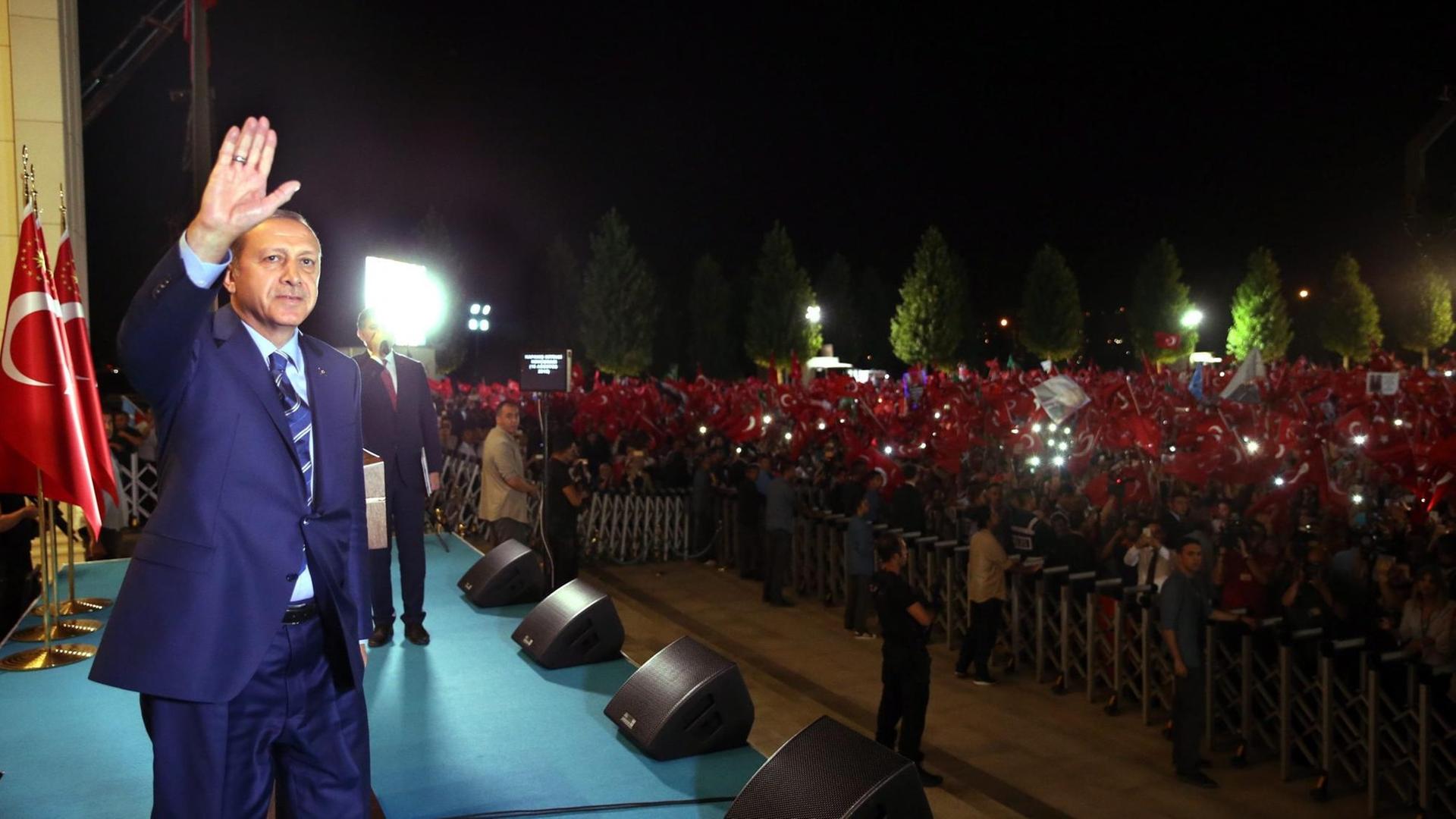 Der türkische Präsident Recep Tayyip Erdogan winkt Menschen mit türkischen Flaggen hinter einer Absperrung zu