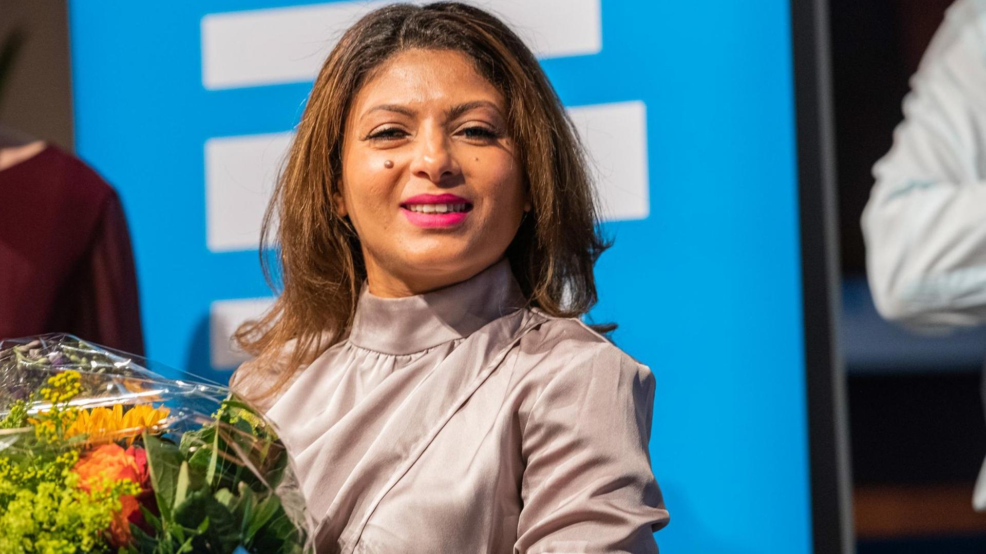 5. Kölner Forum für Journalismuskritik: Die Ehefrau des Bloggers Badawi mit Blumen. Sie lacht in die Kamera.