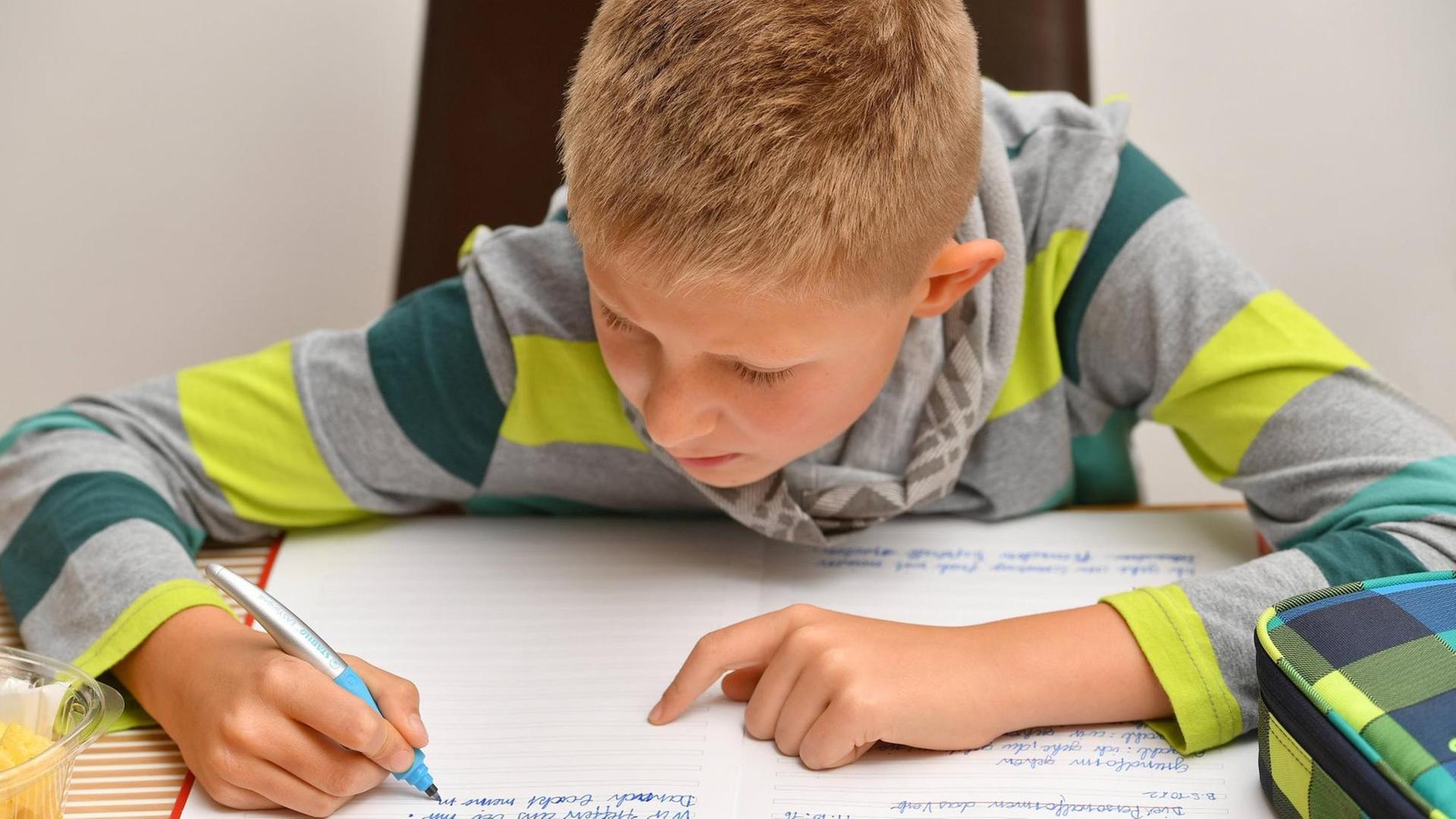 Ein Neunjähriger schreibt in ein Schulheft