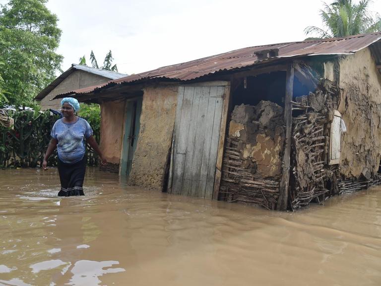 Eine Frau steht in Malfeti im Nordosten haitis knietief im Wasser vor ihrer überschwemmten Hütte.