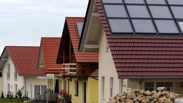 Gezeigt sind gerade fertig gestellte Einfamilienhäuser in einem Neubaugebiet mit Solaranlagen auf dem Dach.