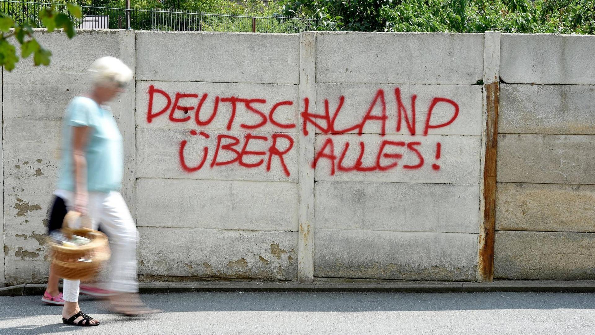 Ein Graffiti an einer Mauer mit der Aufschrift "Deutschland über alles" in roter Farbe.