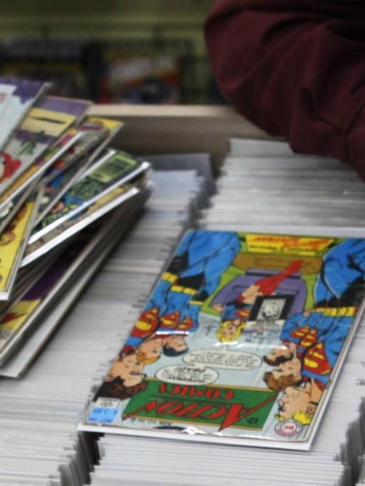 Ein Mann durchsucht eine Auslage mit Comic-Heften in einem Comic-Shop in der US-Stadt Cincinnati. Auf der Auslage befindet sich bereits ein Stapel Comics.