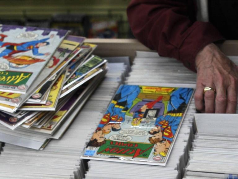 Ein Mann durchsucht eine Auslage mit Comic-Heften in einem Comic-Shop in der US-Stadt Cincinnati. Auf der Auslage befindet sich bereits ein Stapel Comics.