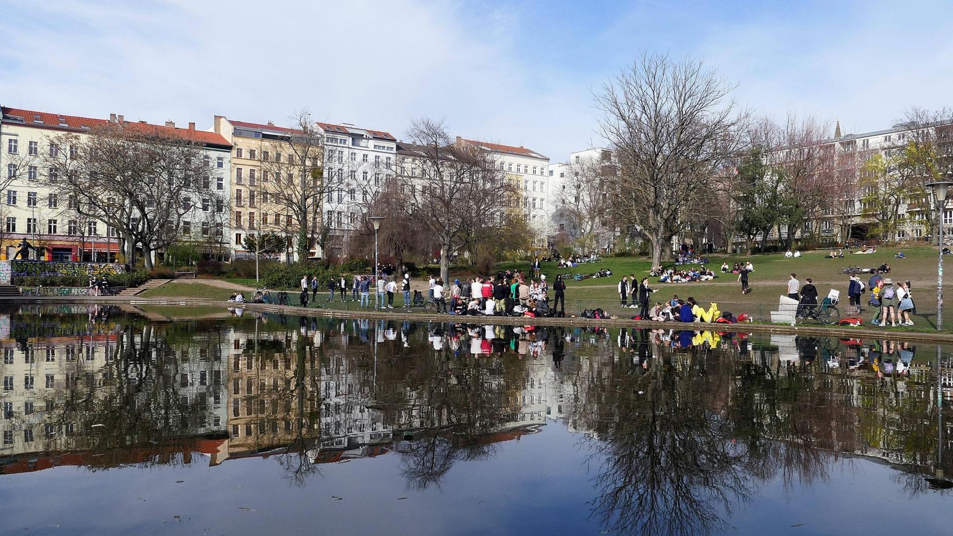 Im Park am Weinbergsweg in Berlin sitzen viele Menschen zum Teil dicht nebeneinander