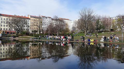 Im Park am Weinbergsweg in Berlin sitzen viele Menschen zum Teil dicht nebeneinander