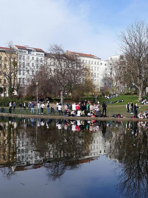 Im Park am Weinbergsweg in Berlin sitzen viele Menschen zum Teil dicht nebeneinander