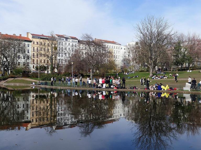 Im Park am Weinbergsweg in Berlin sitzen viele Menschen zum Teil dicht nebeneinander