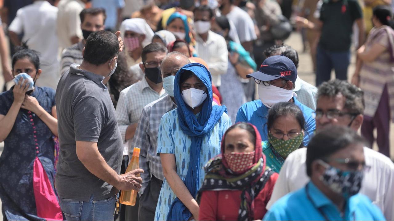 Viele Menschen laufen in Mumbai auf einer Straße.