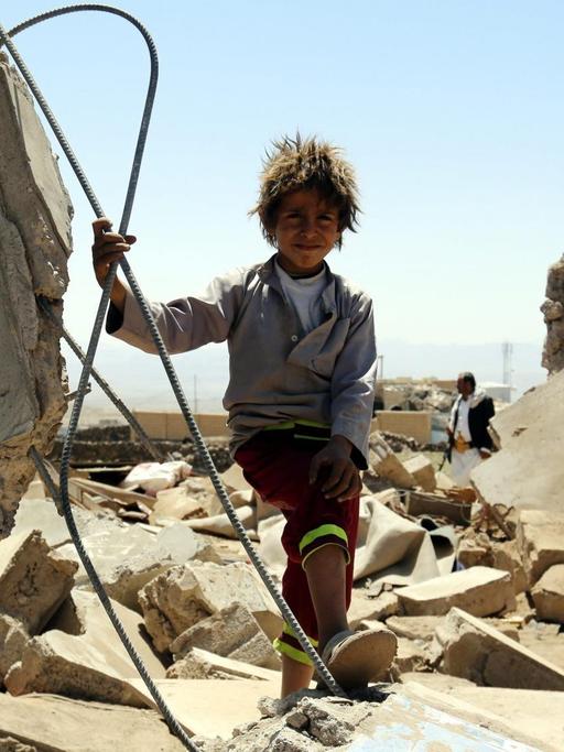 Ein Junge steht im Jemen zwischen Häusertrümmern.