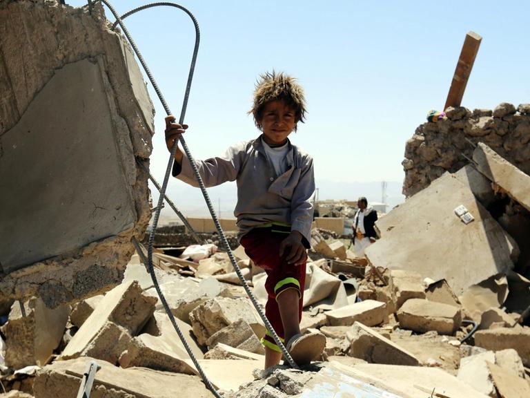 Ein Junge steht im Jemen zwischen Häusertrümmern.