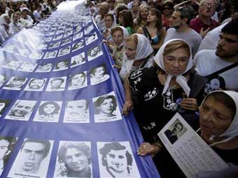 Die Menschenrechtsorganisationen "Großmütter der Plaza de Mayo" und "Mütter der Plaza de Mayo" tragen ein Plakat mit Personen, die während der Militärdiktatur  verschwanden. 