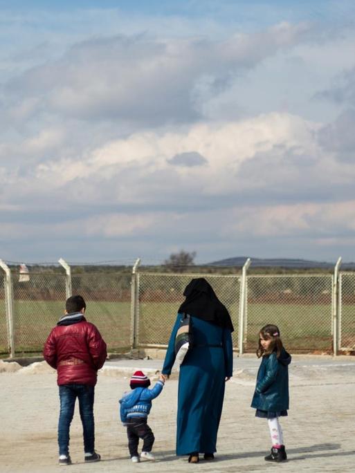 Eine syrische Flüchtlingsfamilie steht am Grenzzaun zum Nachbarland Türkei in der NÄhe der türkischen Stadt Kilis.