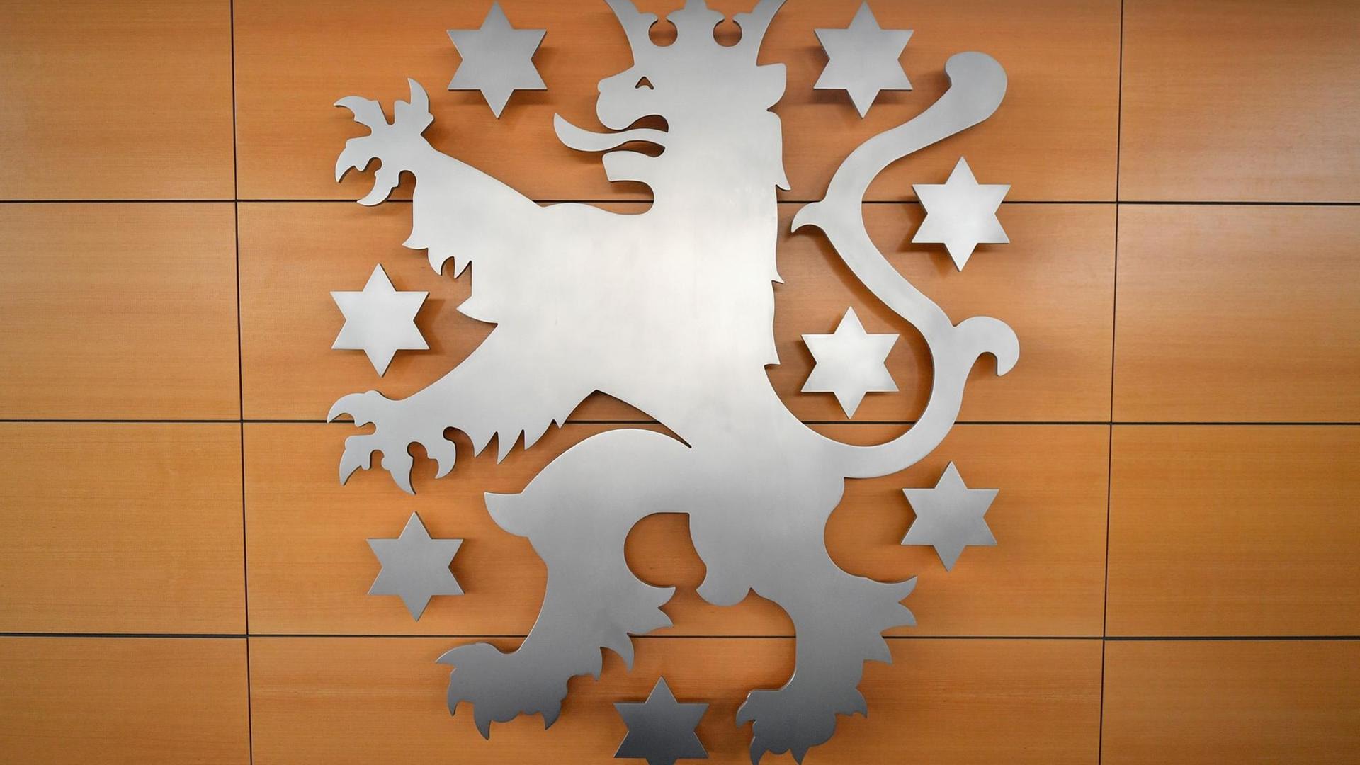 Das silberne Wappen an einer braungetäfelten Wand zeigt einen gekrönten Löwen, um ihn herum mehrere Sterne.