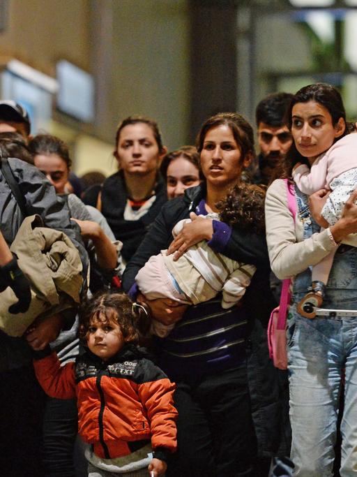 Flüchtlinge, darunter viele Frauen und Kinder, kommen am Hauptbahnhof in München an und gehen von Polizisten begleitet durch den Bahnhof.