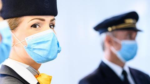 Frau in Stewardessuniform blickt in die Kamera