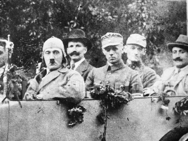 Das Schwarz-weiß-Foto zeigt Adolf Hitler mit den Freikorpsoffizieren Ulrich Graf, Major Buch und Christian Weber in einem offenen Wagen.