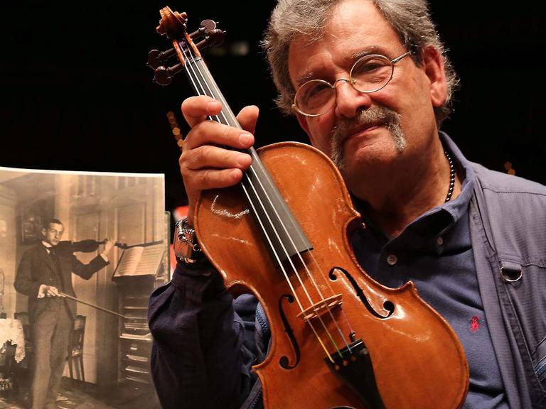 Geigenbauer Amnon Weinstein mit einer von ihm restaurierten Violine bei der Ausstellung "Violins of Hope" in Monaco.