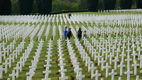 Besucher gehen zwischen den Grabkreuzen auf dem französischen Soldatenfriedhof am Beinhaus von Douaumont (Hintergrund) aus dem Ersten Weltkrieg nahe Verdun/Frankreich (Region Lorraine), aufgenommen am 25.04.2014.